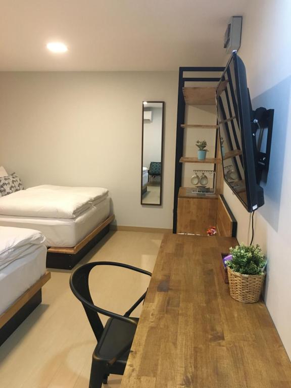 A twin room with a long wooden desk, television and open shelving.