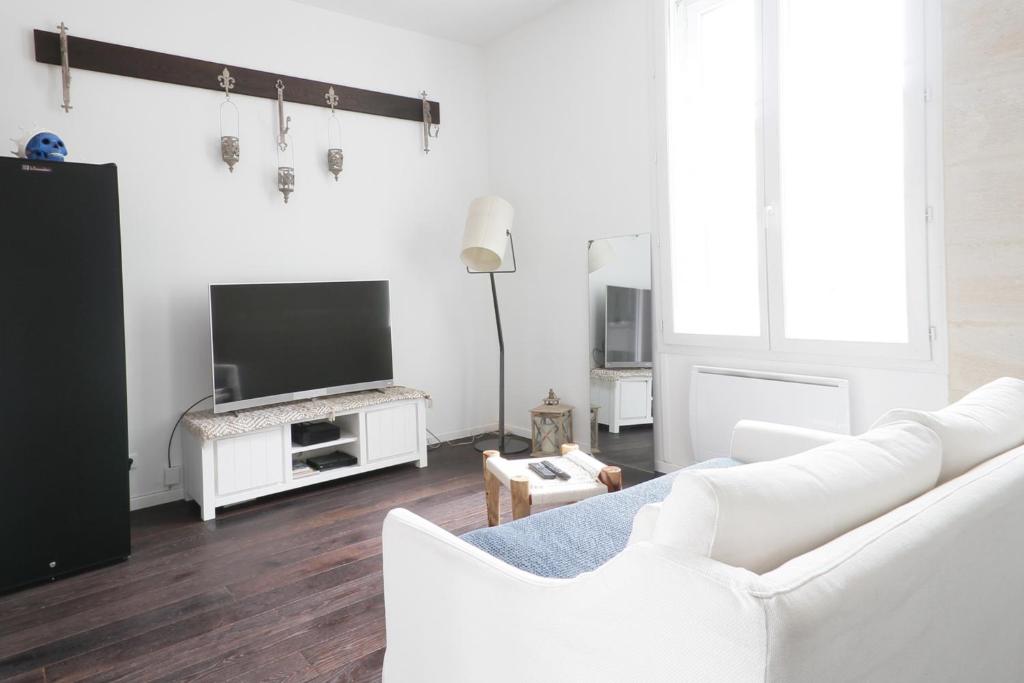 a living room with white furniture and a flat screen tv at Appartement centre de Bordeaux Clim et tram in Bordeaux