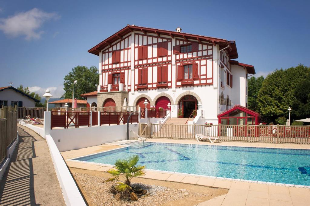 uma casa com piscina em frente a uma casa em Hôtel & Résidence Vacances Bleues Orhoïtza em Hendaye