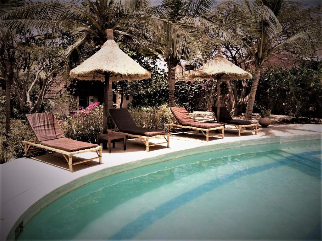 a group of chairs and umbrellas next to a pool at Auberge Keurmariguen in Somone