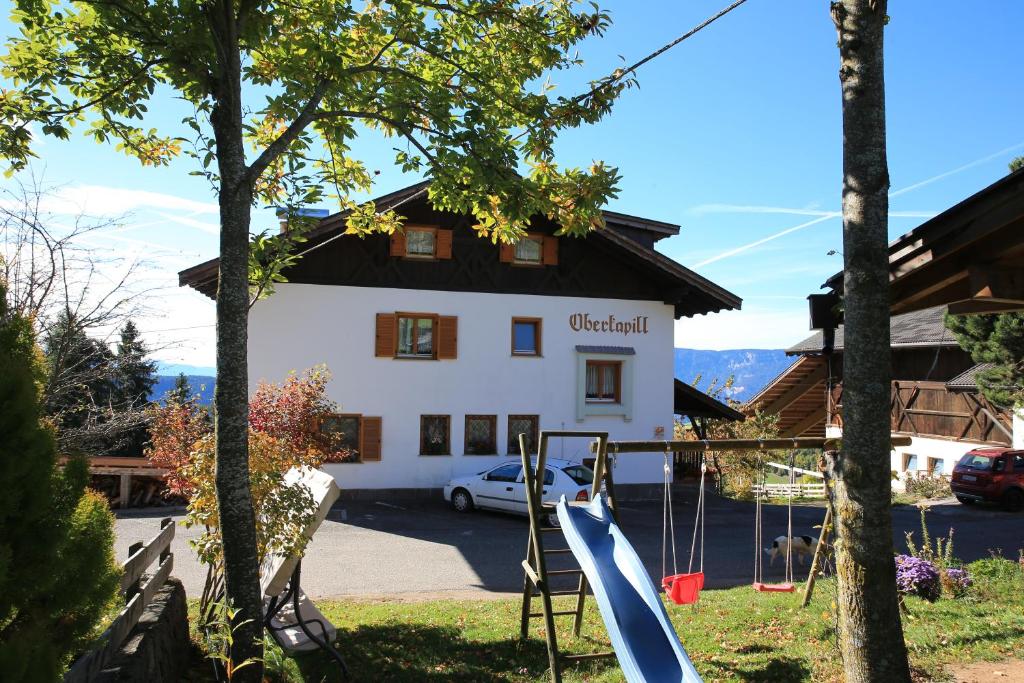 um edifício com um parque infantil em frente em Oberkapillhof em Meltina