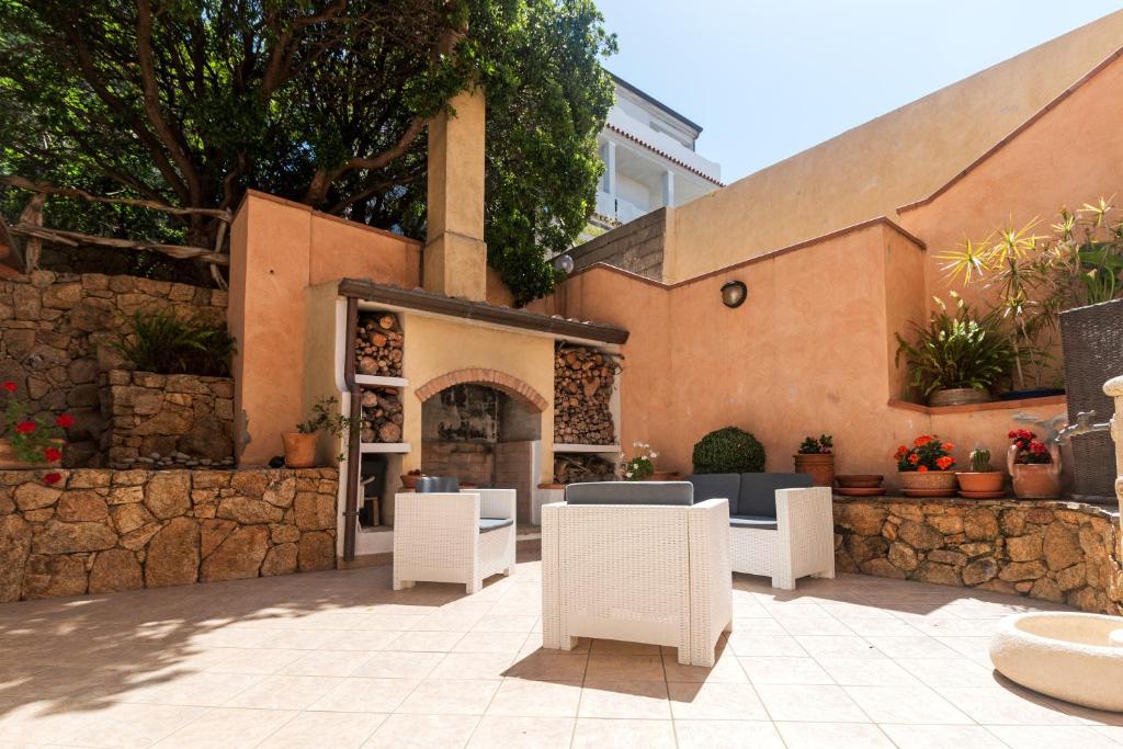 a patio with white chairs and a stone wall at Melalidone in Orosei