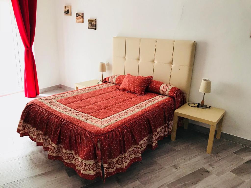 1 dormitorio con 1 cama grande con colcha roja en Casa Rural Setenil, en Setenil