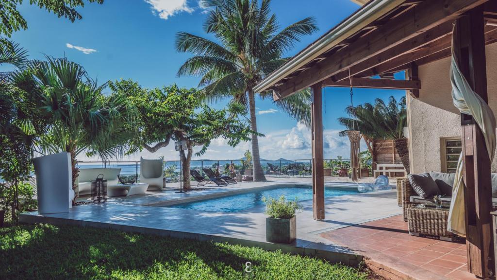 einen Pool mit Palmen und ein Haus in der Unterkunft Villa d’ô in Majikavo Koropa