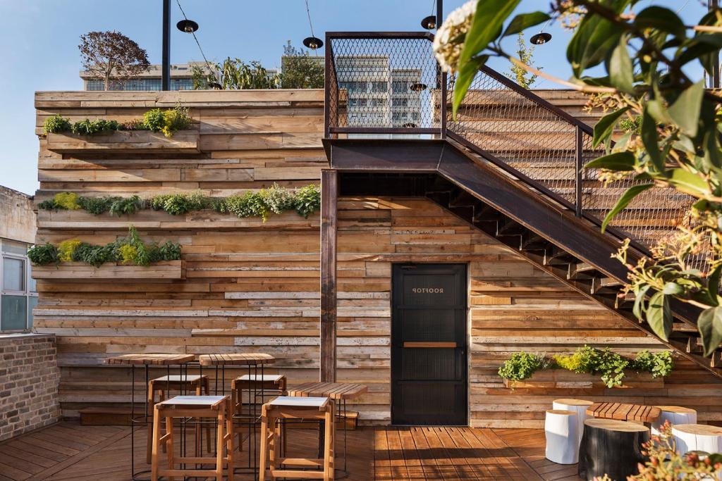 a wooden building with a staircase and tables and chairs at The Vera in Tel Aviv