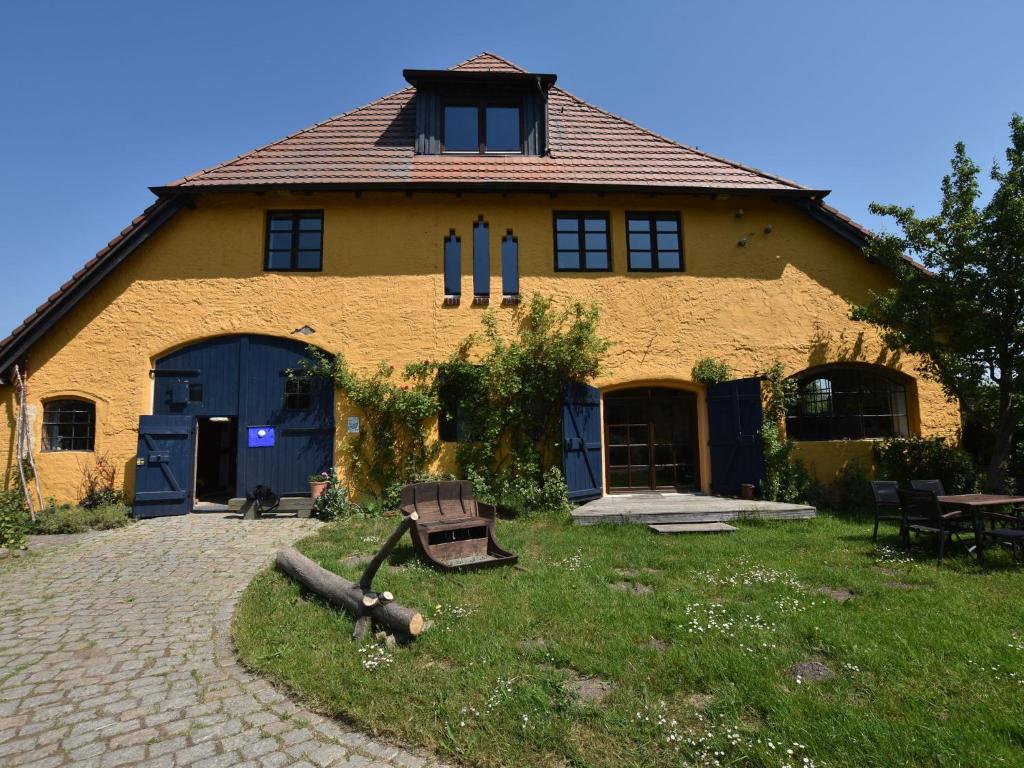 a large yellow building with blue doors and windows at Cozy Apartment in Buschenhagen with Sauna in Buschenhagen