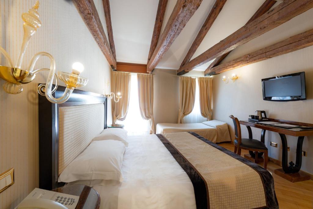a bedroom with a bed and a desk and a television at Hotel Paganelli in Venice