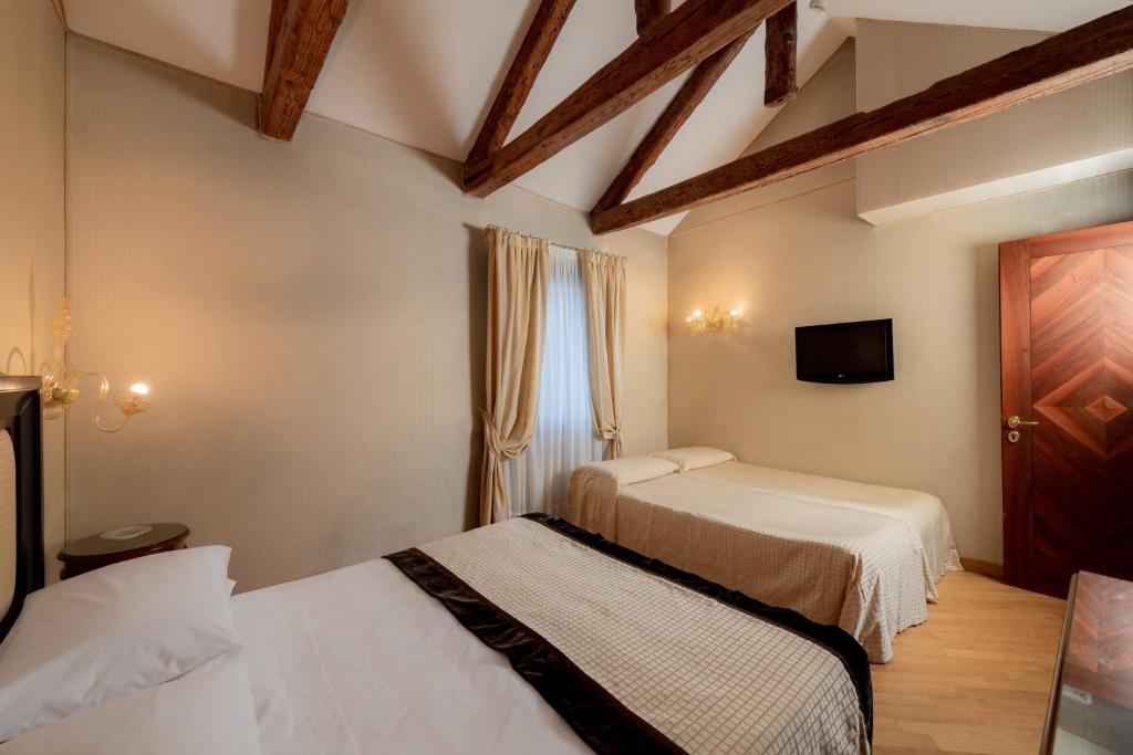a hotel room with two beds and a tv at Hotel Paganelli in Venice