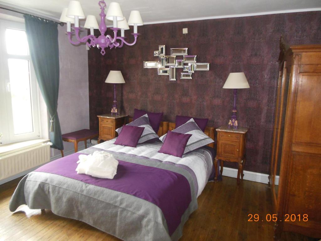 ein Schlafzimmer mit einem großen Bett mit violetter Bettwäsche in der Unterkunft Au trou perdu in Corroy-le-Château
