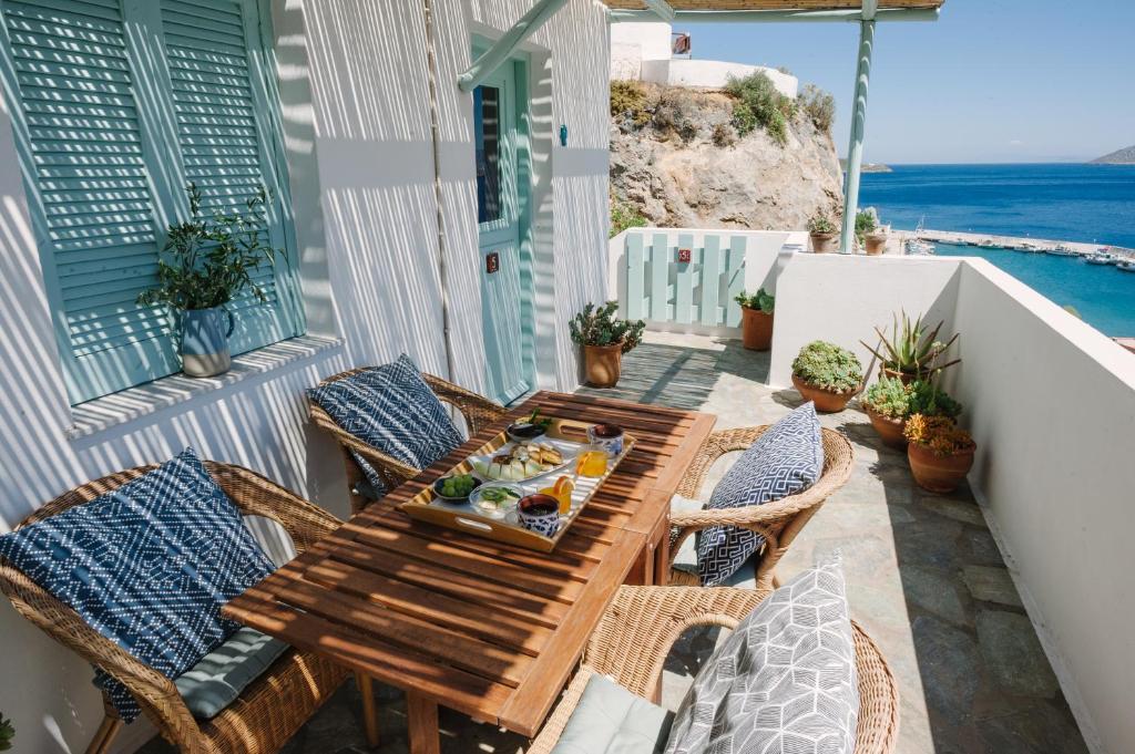una mesa de madera y sillas en un balcón con vistas al océano en Asterias, en Panteli