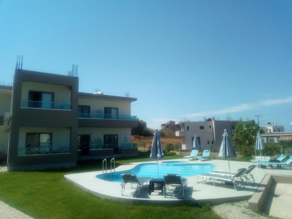 a swimming pool with chairs and a house at Efrilias Studios & Apartments in Kissamos