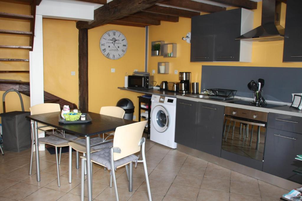 a kitchen with a table and chairs and a clock on the wall at Le Bleuet in Ouistreham