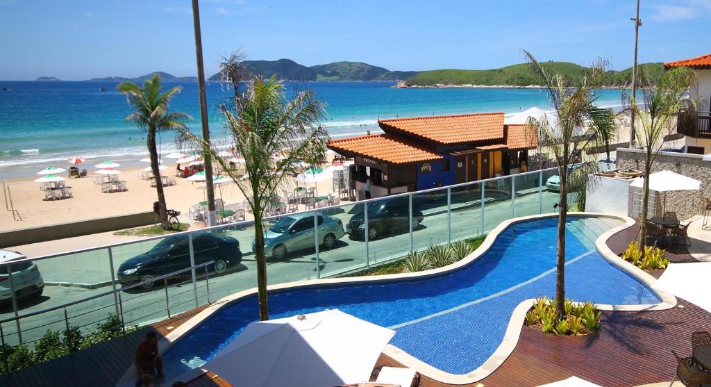um resort com uma piscina ao lado de uma praia em Paradiso Peró Praia Hotel em Cabo Frio