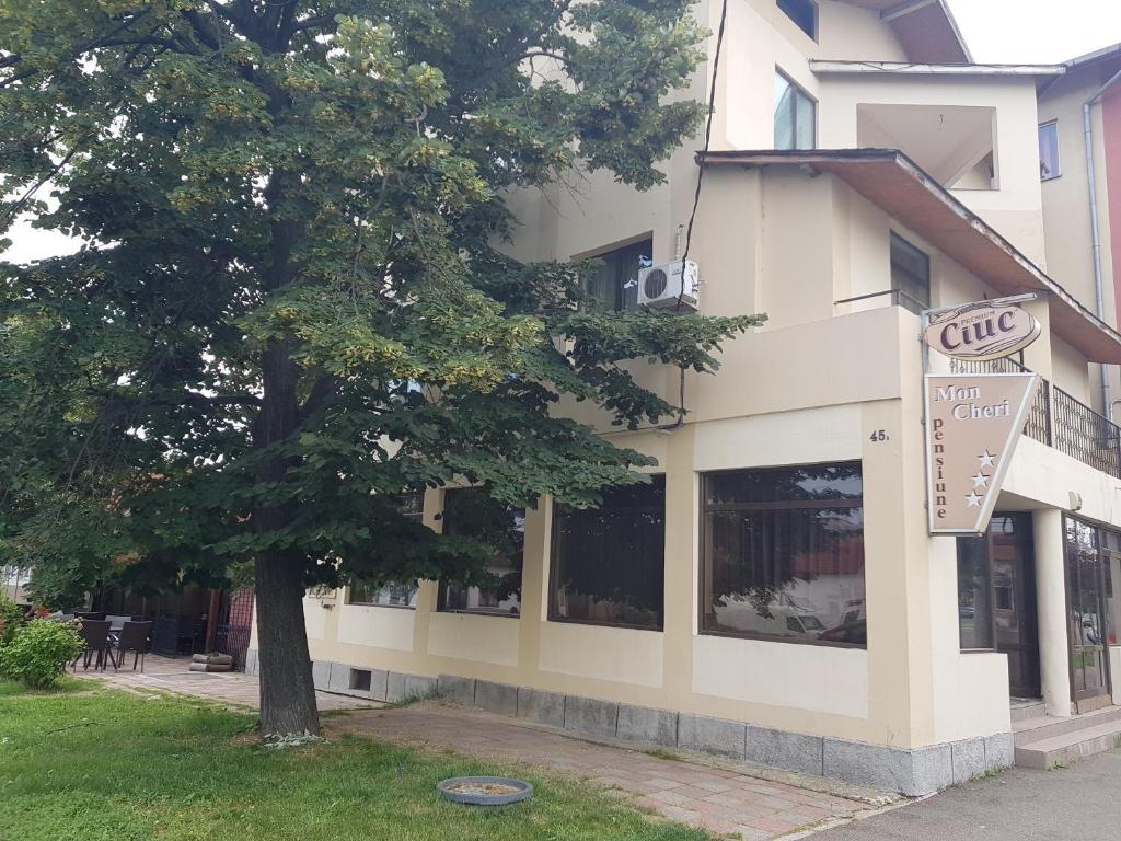 un edificio con un árbol delante de él en Mon Cheri, en Drobeta-Turnu Severin