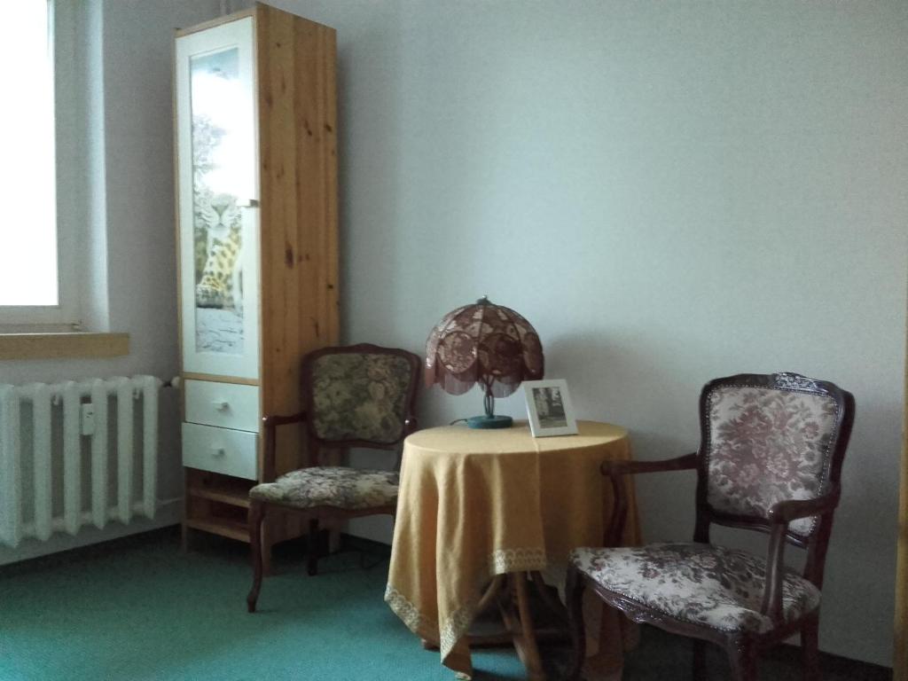 ポズナンにあるHotellik Sobieskiegoの椅子2脚とテーブル(ランプ付)が備わる客室です。
