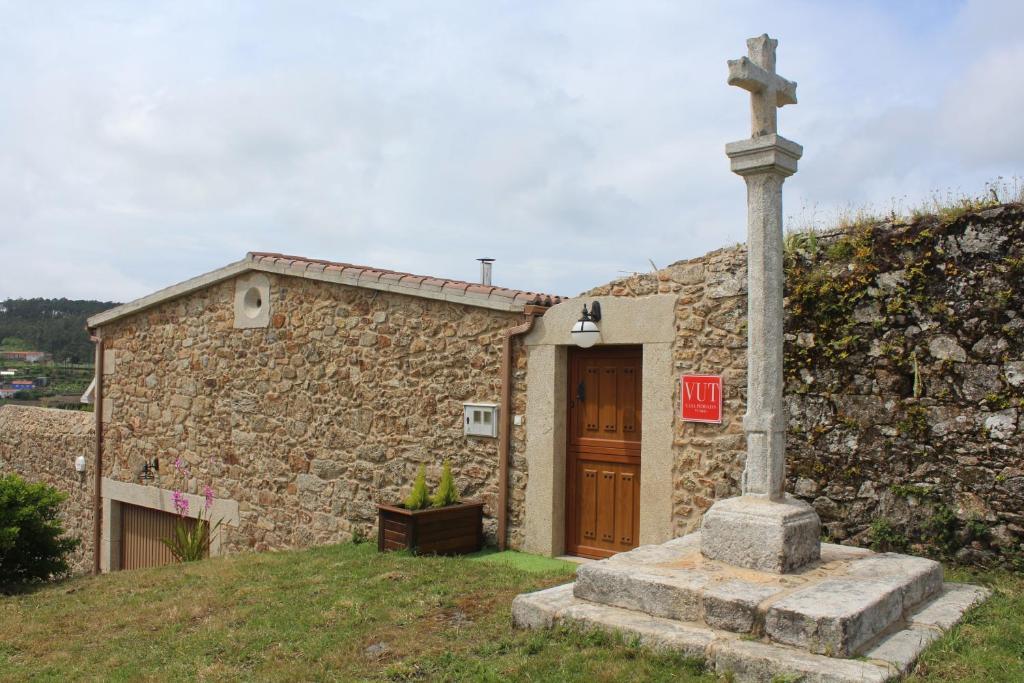 a church with a cross next to a stone building at Casal Pedrajás in Muxia