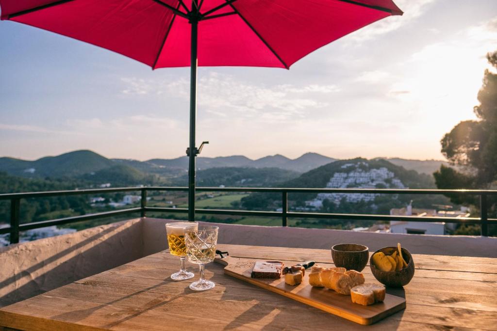 una mesa con un plato de comida y una sombrilla roja en Apartamentos Catharina Maria en Cala Llonga