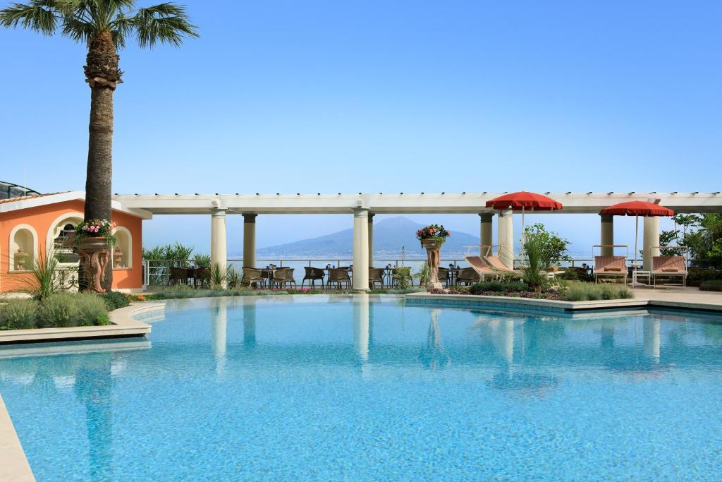 une grande piscine avec des palmiers et un pont dans l'établissement Grand Hotel Royal, à Sorrente