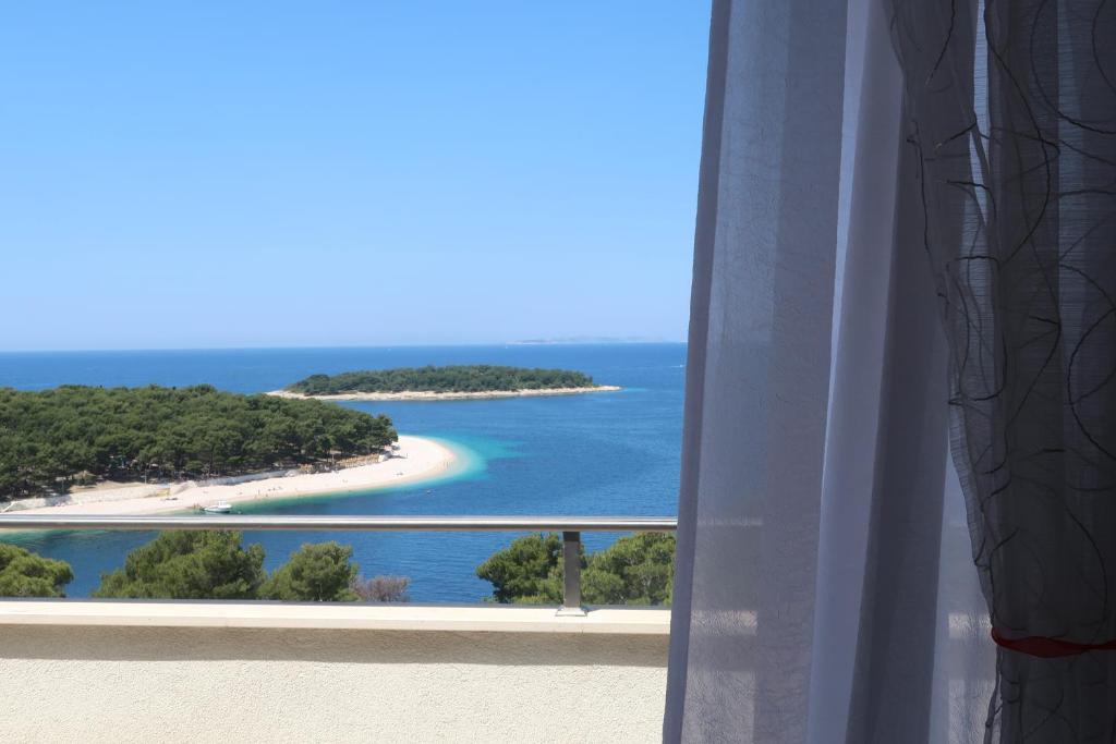 una ventana con vistas a la playa y al océano. en Apartments Maras, en Primošten