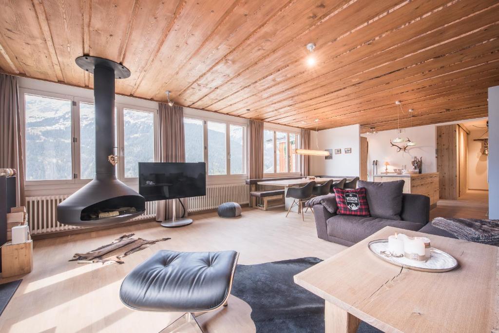 un soggiorno con soffitto in legno e camino di Schweizerheim Residence 11 a Wengen