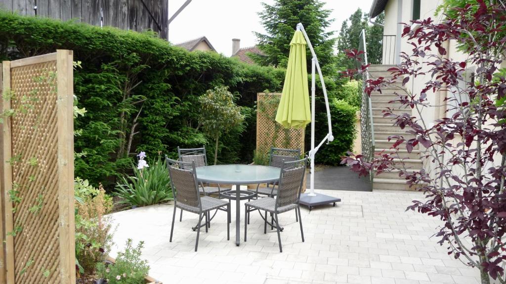 eine Terrasse mit einem Tisch, Stühlen und einem Sonnenschirm in der Unterkunft l'ANNEXE in Verdigny