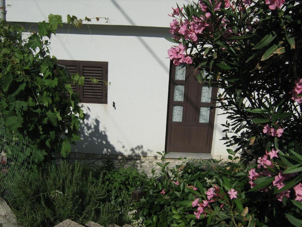eine Tür eines weißen Hauses mit rosa Blumen in der Unterkunft Podmartine in Baška
