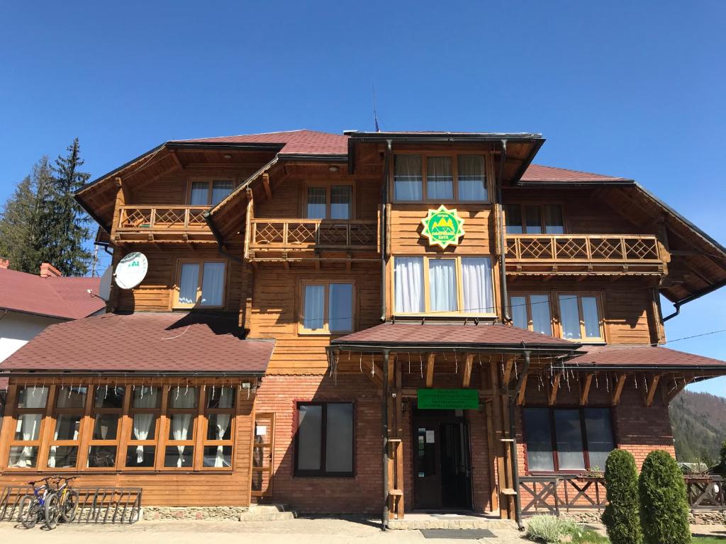 un grand bâtiment en bois avec une horloge. dans l'établissement Smerekova Hata, à Slavsko