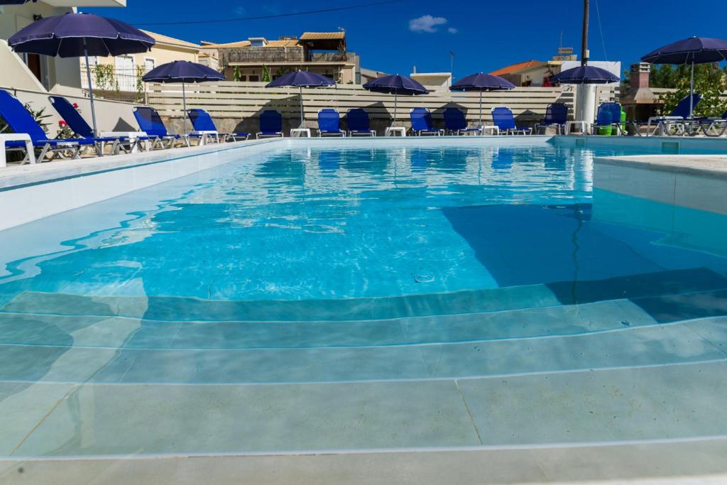 a swimming pool with blue chairs and umbrellas at Laganas Dreams 2 in Laganas