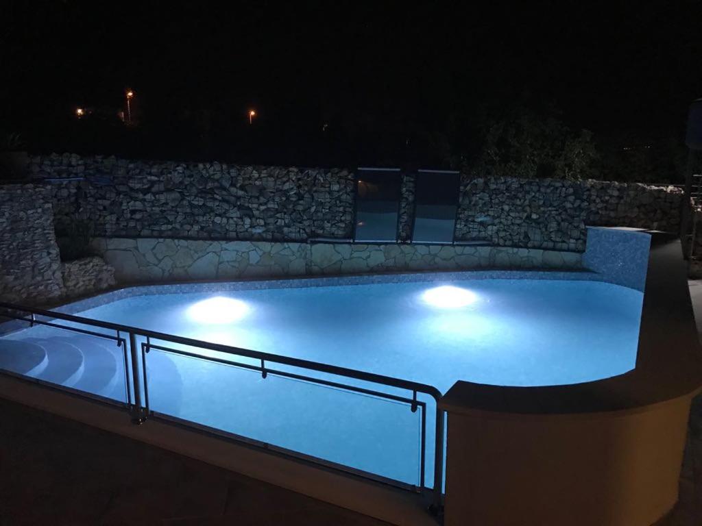 uma piscina iluminada à noite com luzes em Apartment Kale em Šibenik