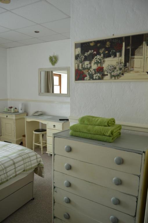 a bedroom with a dresser with a green towel on it at Caulfields Hotel in Burry Port
