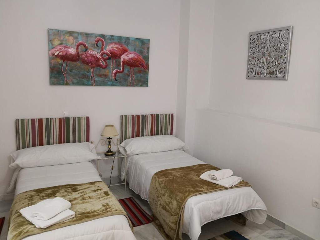 a room with two beds and a picture of flamingos at Big House Jerez in Jerez de la Frontera
