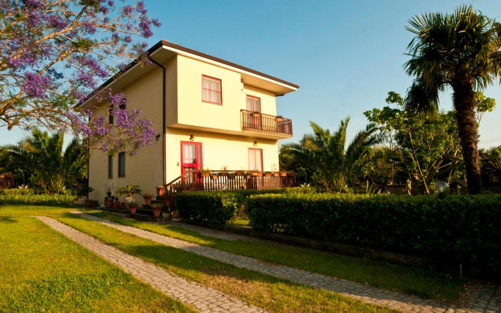a white house with a red door and a pathway at B&B Villa dei Fiori in SantʼEufemia Lamezia