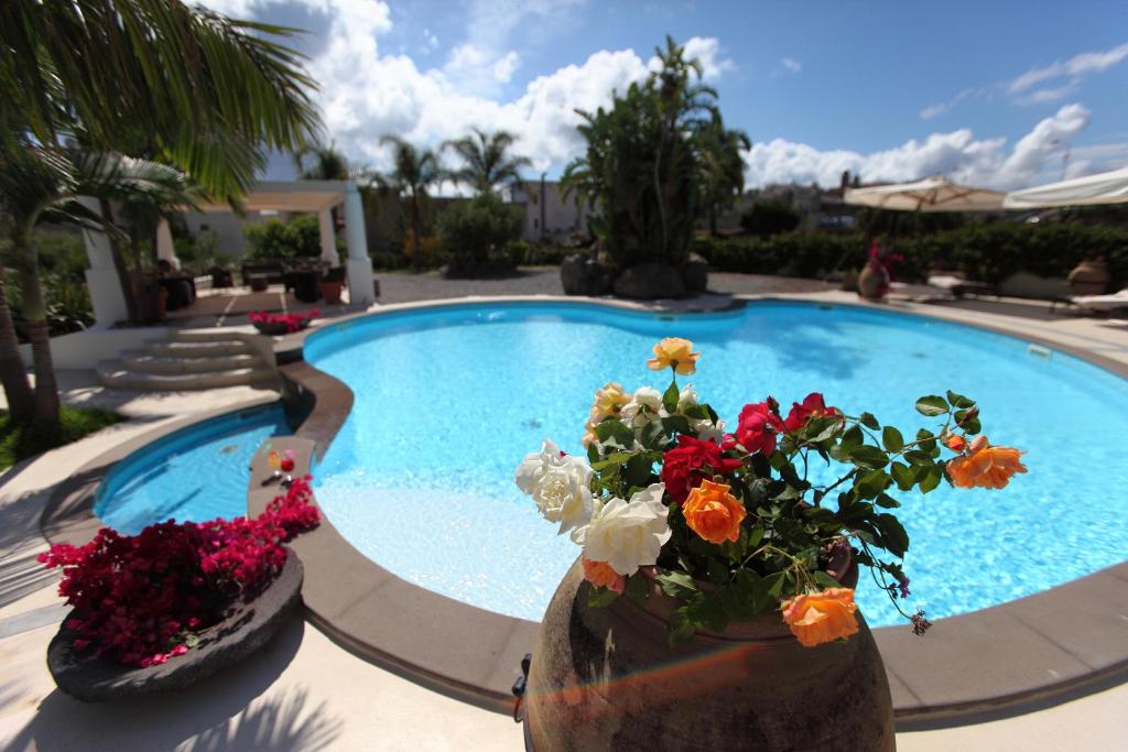 a swimming pool with flowers in vases next to it at Residence Hotel La Giara in Lipari