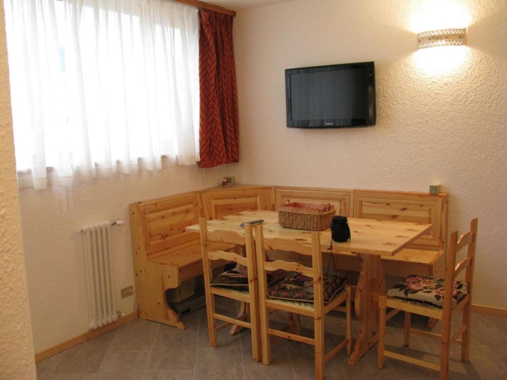 ein Esszimmer mit einem Tisch und einem TV an der Wand in der Unterkunft Bilocale Fronte Piste - Appartamentiflarida Sansicario Alto in San Sicario