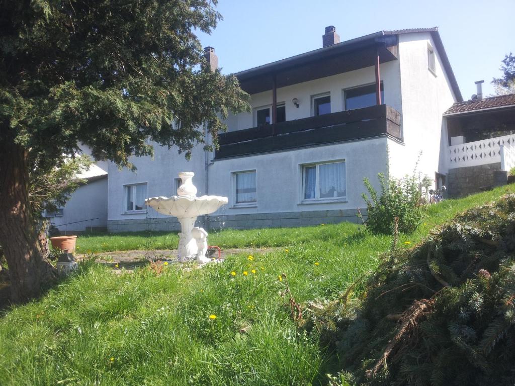 a white fountain in the grass in front of a house at Ferienwohnung Sauer in Fritzlar