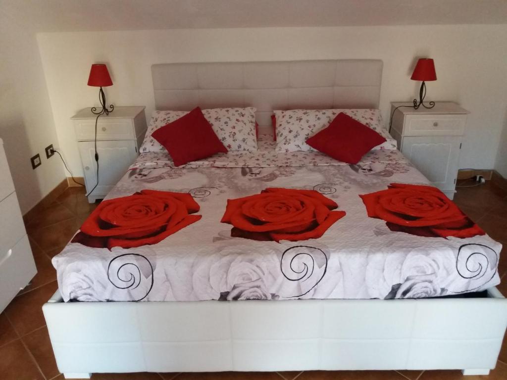 a white bed with three red roses on it at Mansardina Sassu in Alghero