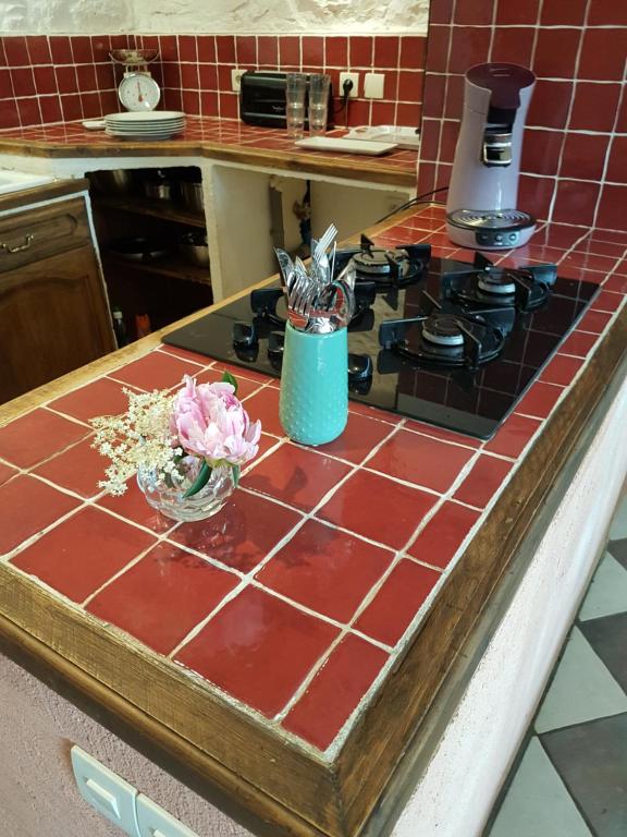 a kitchen counter with a stove and a bowl of flowers at Le Logis De Judicael in Paimpont