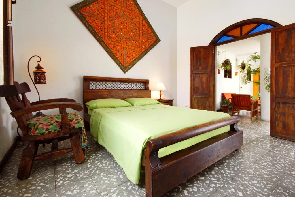 a bedroom with a green bed and a chair at Casa Ruta Sur in Cali