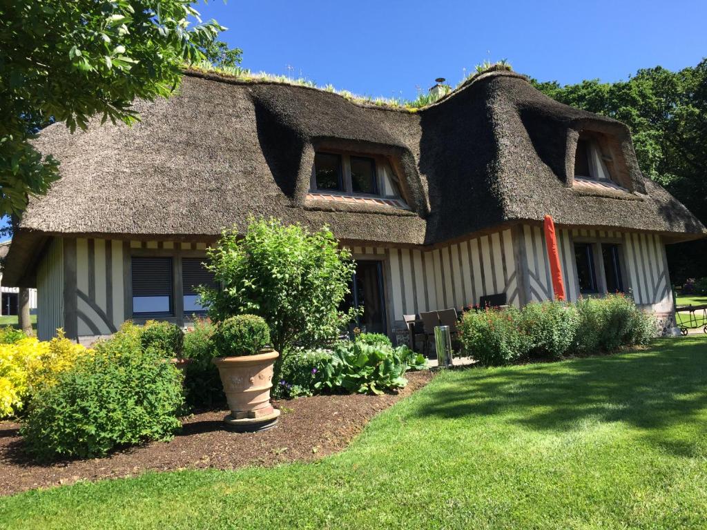 een huis met een rieten dak en een tuin bij Holiday home Le clos du phare in Saint-Samson-de-la-Roque