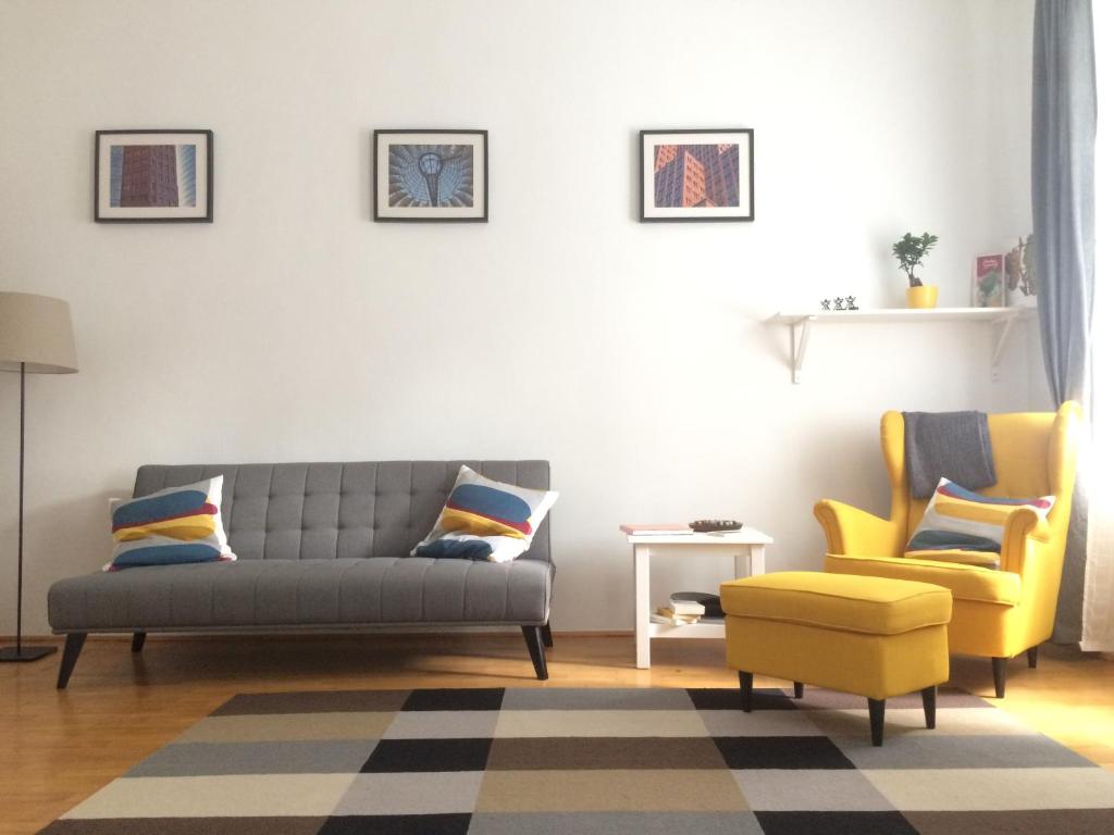 a living room with a couch and two yellow chairs at Enjoy Apartman in Sopron