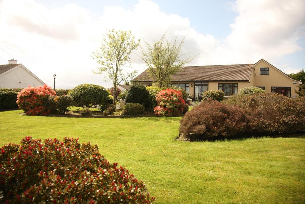 a house with a yard with bushes and flowers at Torine House B&B in Killorglin