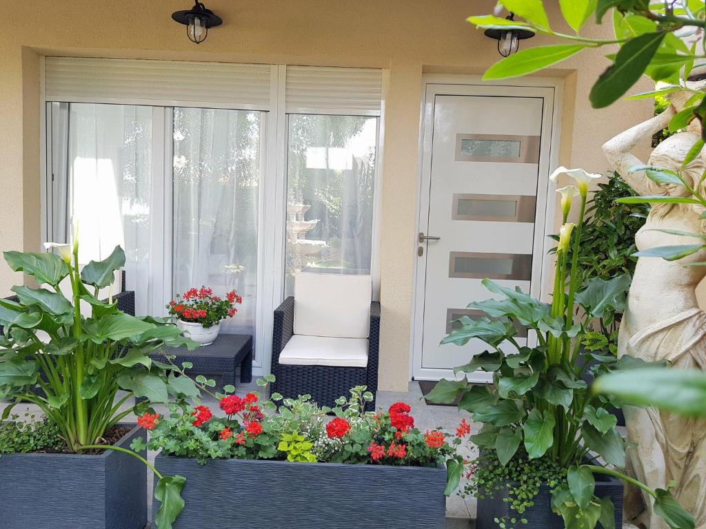 a front porch with flowers and a white chair at 35m2 - 10 min de CDG in Le Thillay