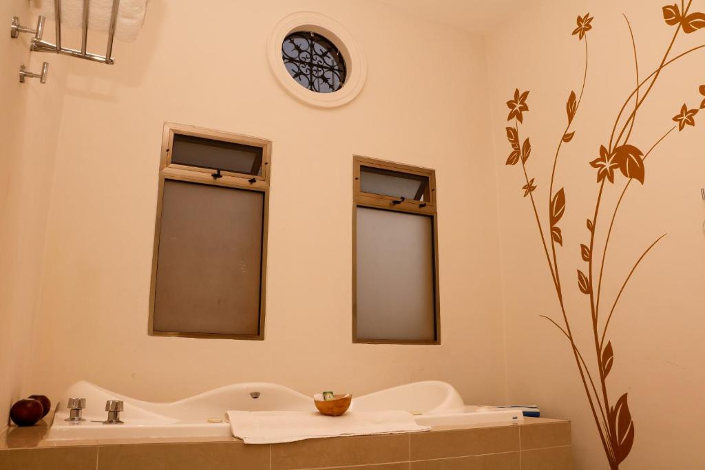 a bathroom with a sink and a clock on the wall at Merida Santiago Hotel Boutique in Mérida