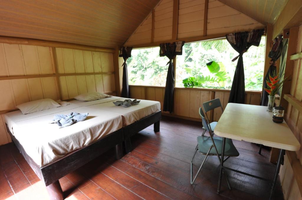 a bedroom with a bed and a table in a room at Complejo Ecoturistico Tamandua in Drake
