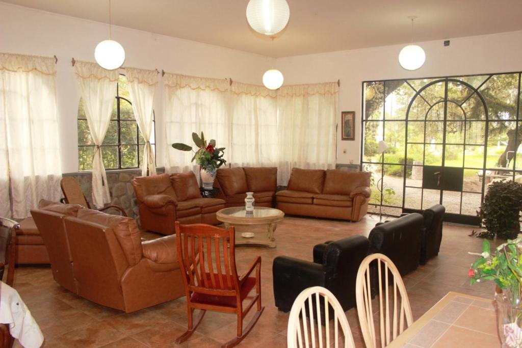 a living room with brown leather furniture and windows at Quinta Valvanera in Salta