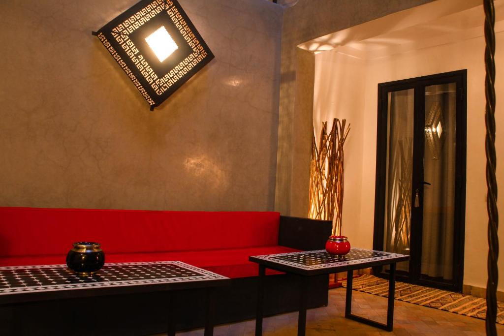 ein Wohnzimmer mit einem roten Sofa und 2 Tischen in der Unterkunft Riad DAR HOME in Marrakesch