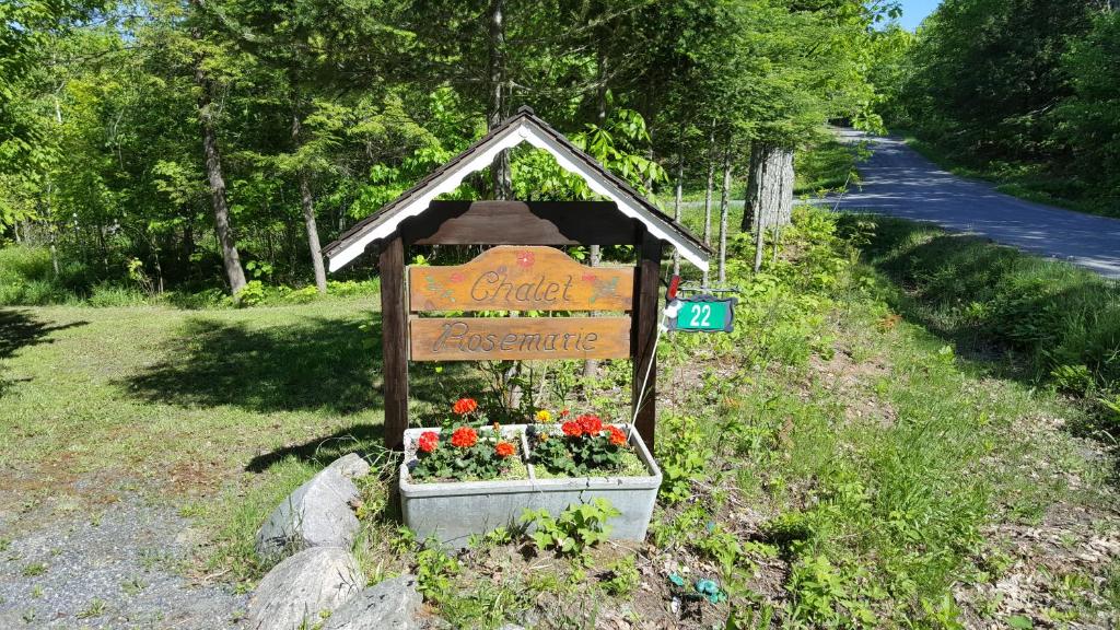 ein Schild im Gras mit Blumen in einer Schachtel in der Unterkunft Chalet Rosemarie in Nobel