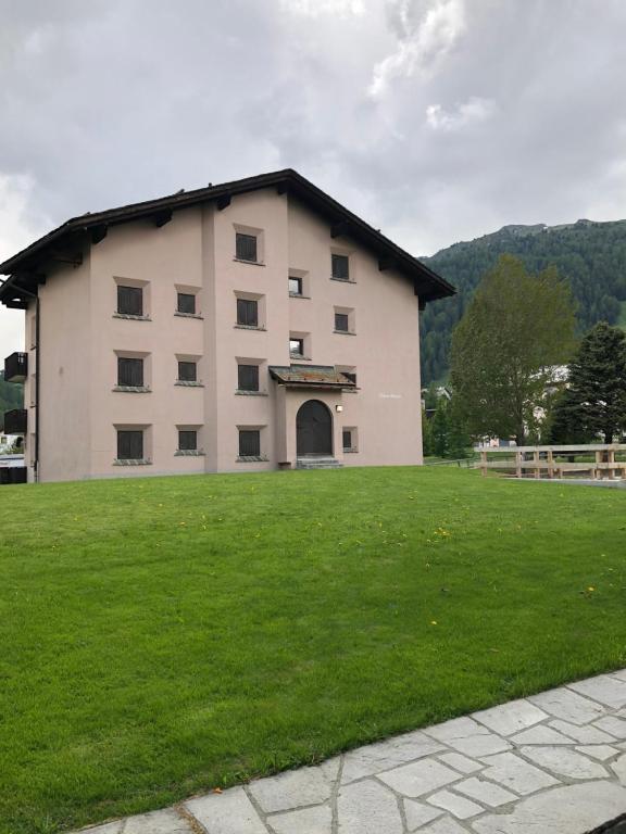 a large building with a grass field in front of it at chesa allegra app g in Celerina