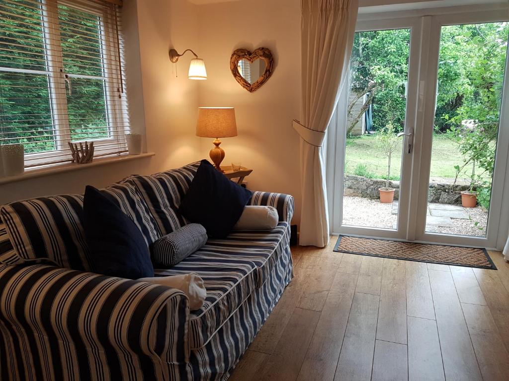 a living room with a couch and a sliding glass door at The Beekeeper's Cottage in Saint Columb Major