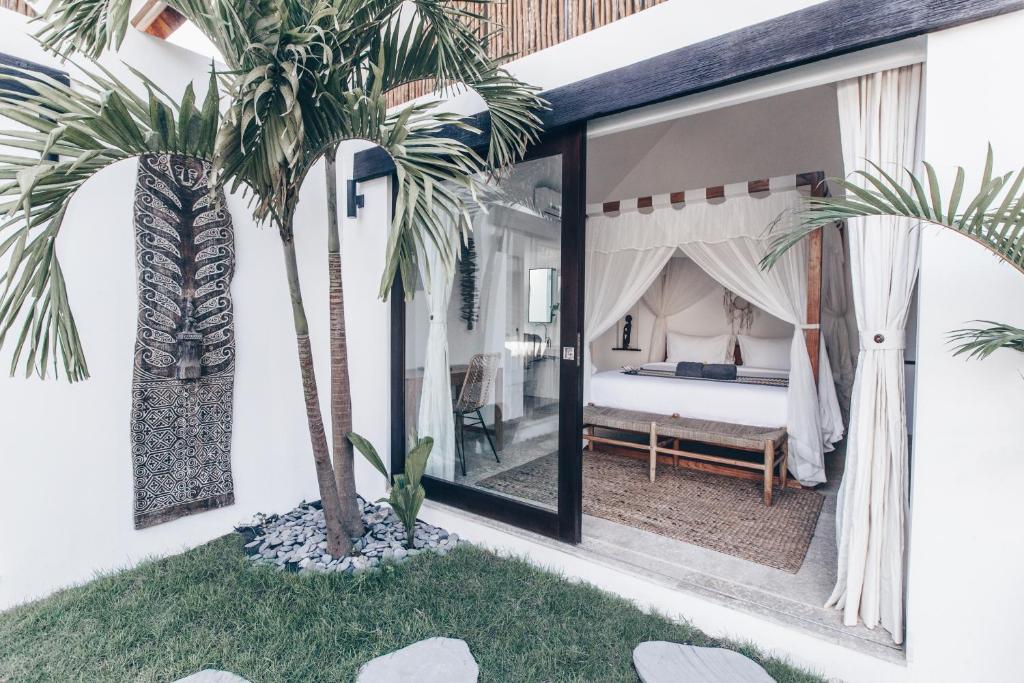 a bedroom with a bed and two palm trees at Beyond Bungalows in Canggu